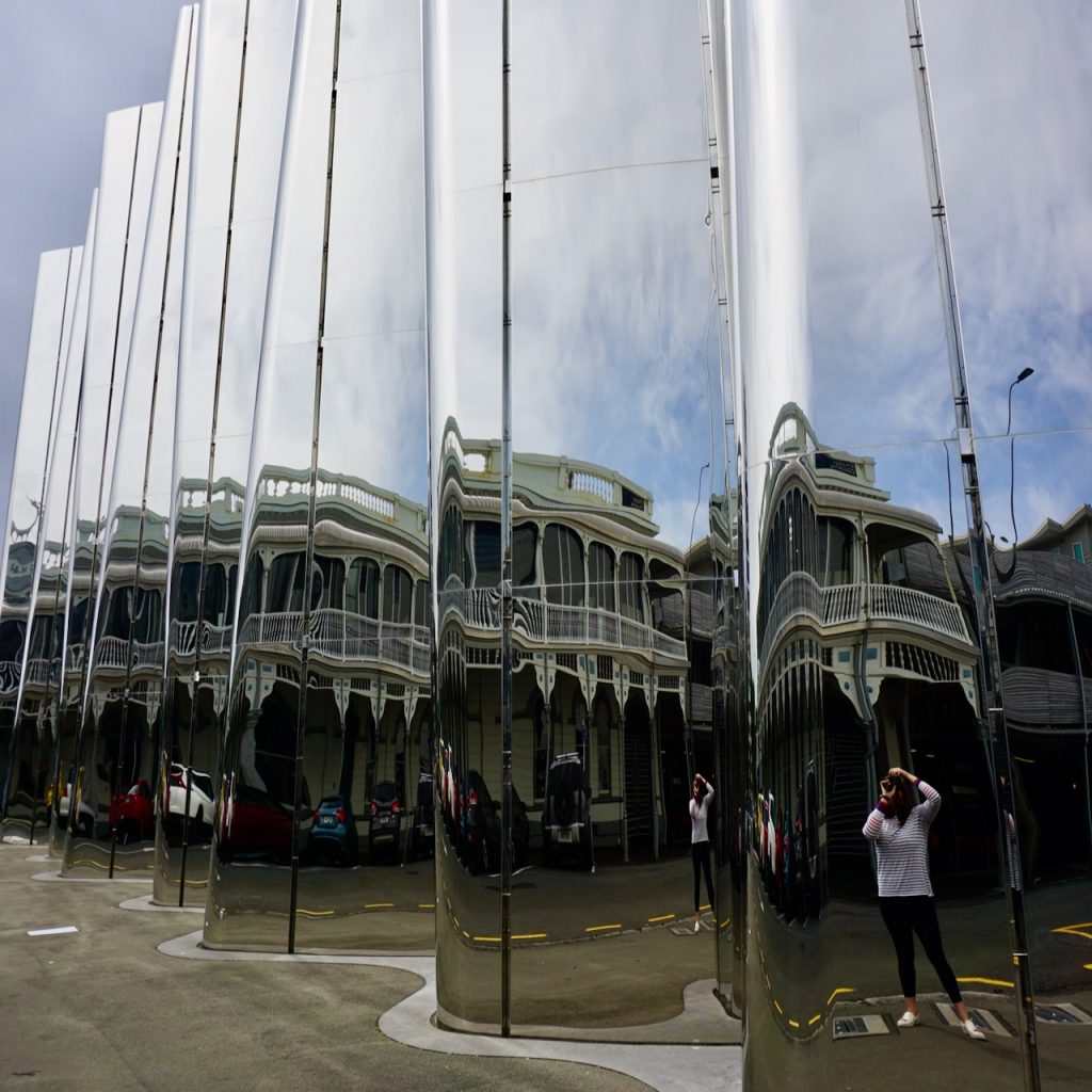 Woman reflected in wavy mirrored building