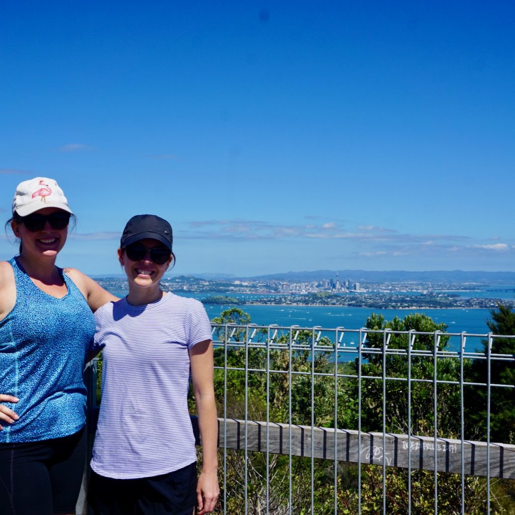 Jessi and Natalie smiling with view of Auckland behind